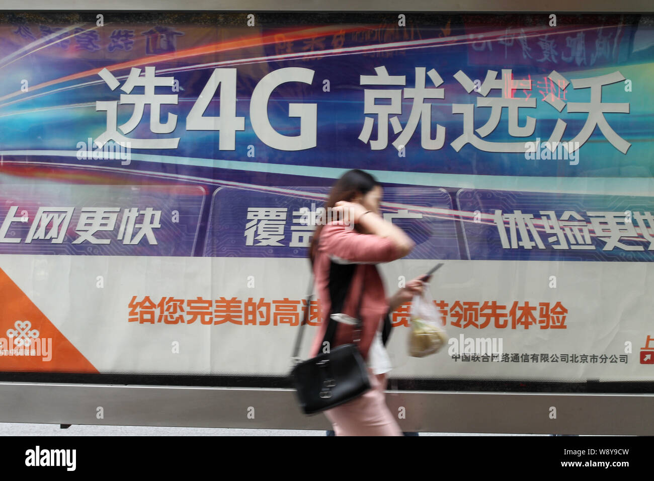 --FILE--un piéton passe devant une publicité pour les réseaux 4G LTE de China Unicom à Beijing, Chine, 10 mai 2014. China Telecom Corp et la Chine Banque D'Images