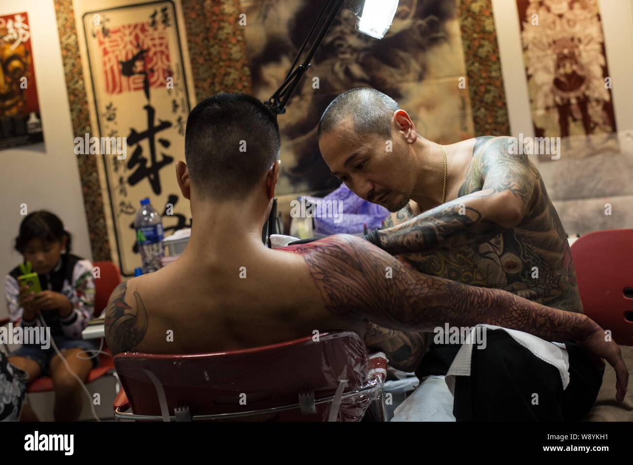 Artiste de tatouage japonais Shige, droite, encres le corps d'un client pendant la deuxième International Hong Kong Convention de Tatouage à Kowloon Tong district, Banque D'Images