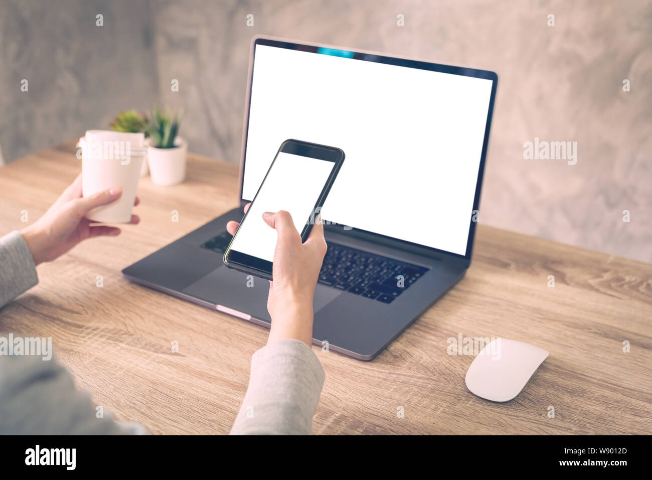 Les femmes Hipster holding phone et l'utilisation de l'ordinateur portable sur une table en bois dans la région de coffee shop. Banque D'Images