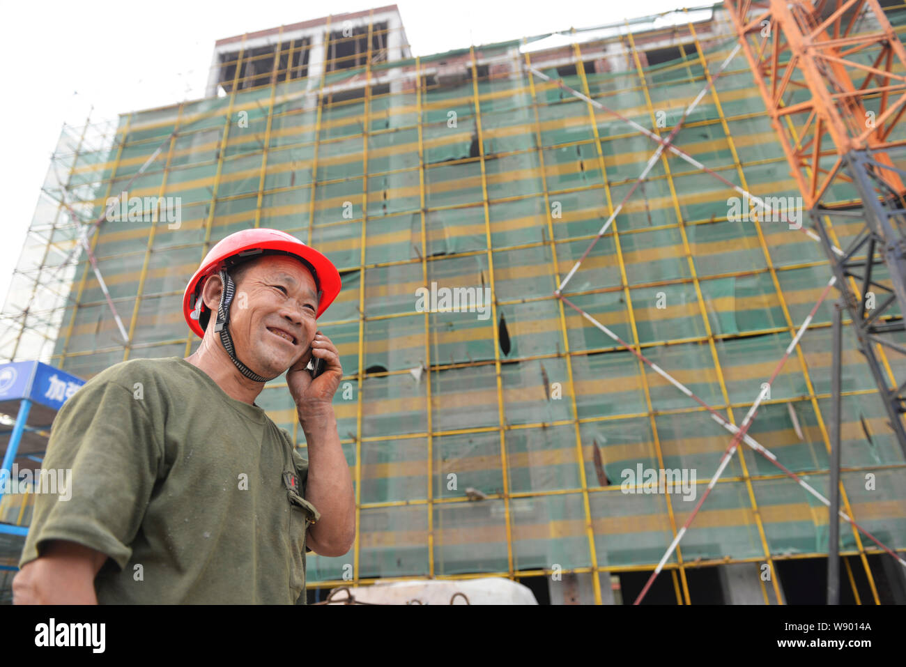 --FILE--un travailleur migrant chinois écoute sur son téléphone portable sur le site de construction d'un projet immobilier à Binzhou City, Shandong Chine de l'est p Banque D'Images