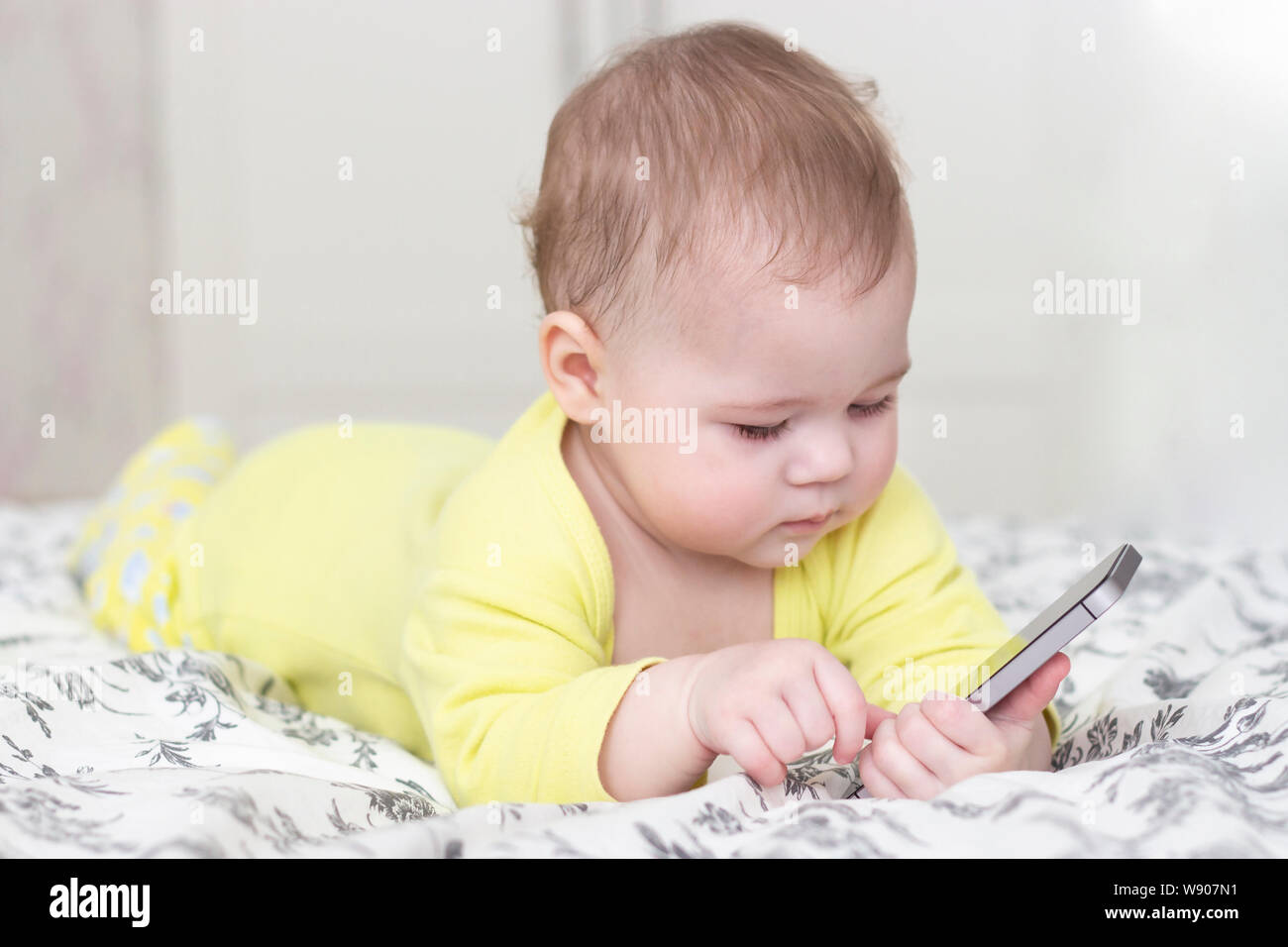 Bebe Fille Garcon Jouant Avec Un Smartphone En Position Allongee Sur Un Lit Un Bebe En Jaune 6 Mois Holding A Mobile Phone Photo Stock Alamy