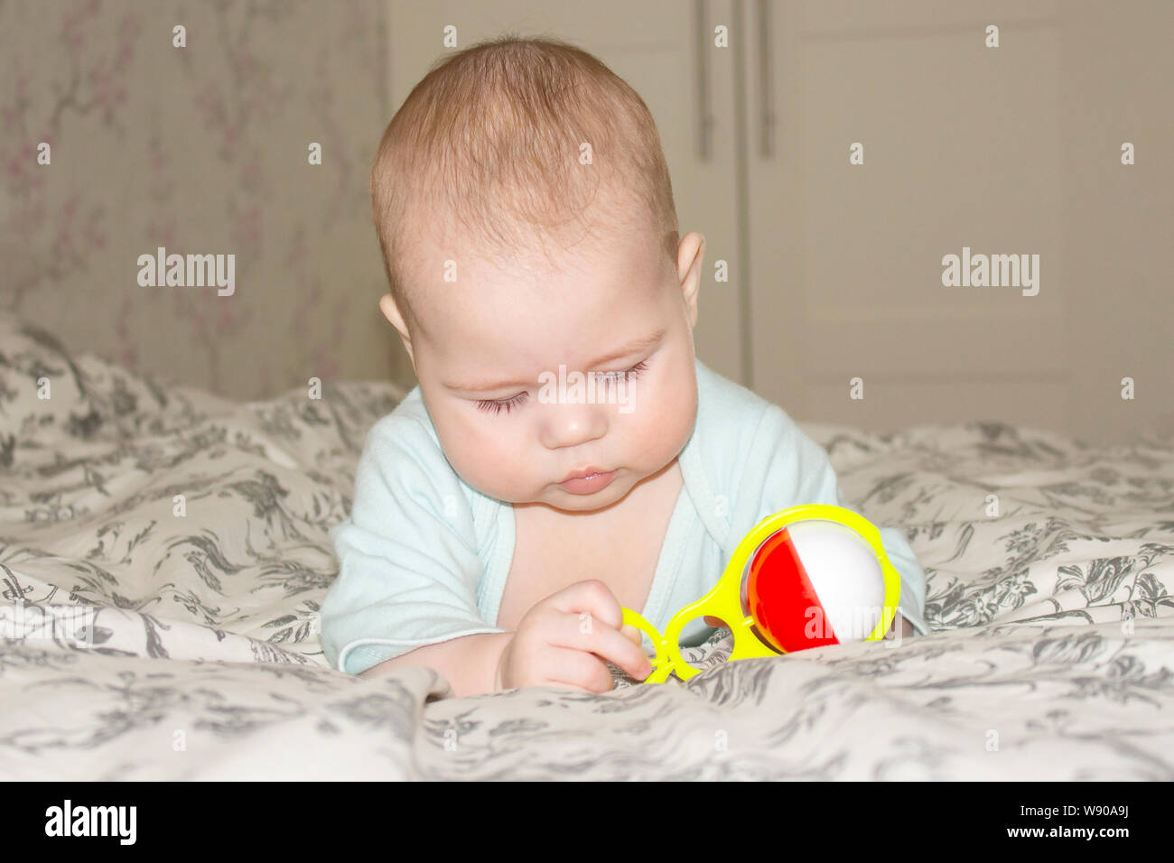 Bébé fille garçon jouer avec un hochet sur le lit. Petit bébé regarde un  jaune rouge jouet. Demi de jeux enfants Photo Stock - Alamy