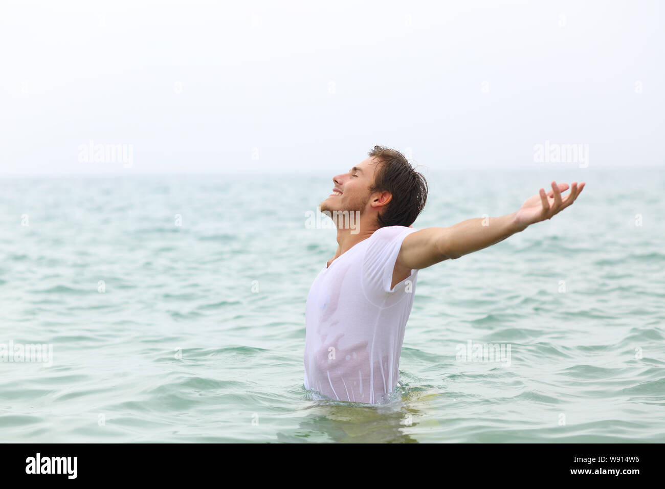 Vue de côté portrait d'un homme heureux qui s'étend sur la plage de baignade ams Banque D'Images