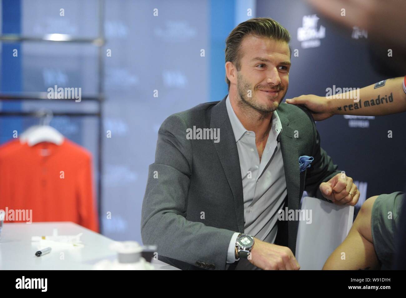 Star du football anglais David Beckham sourire alors qu'il regarde le tatouage d'un ventilateur pendant un événement promotionnel pour David Beckham Bodywear pour H&M à Pékin, Banque D'Images