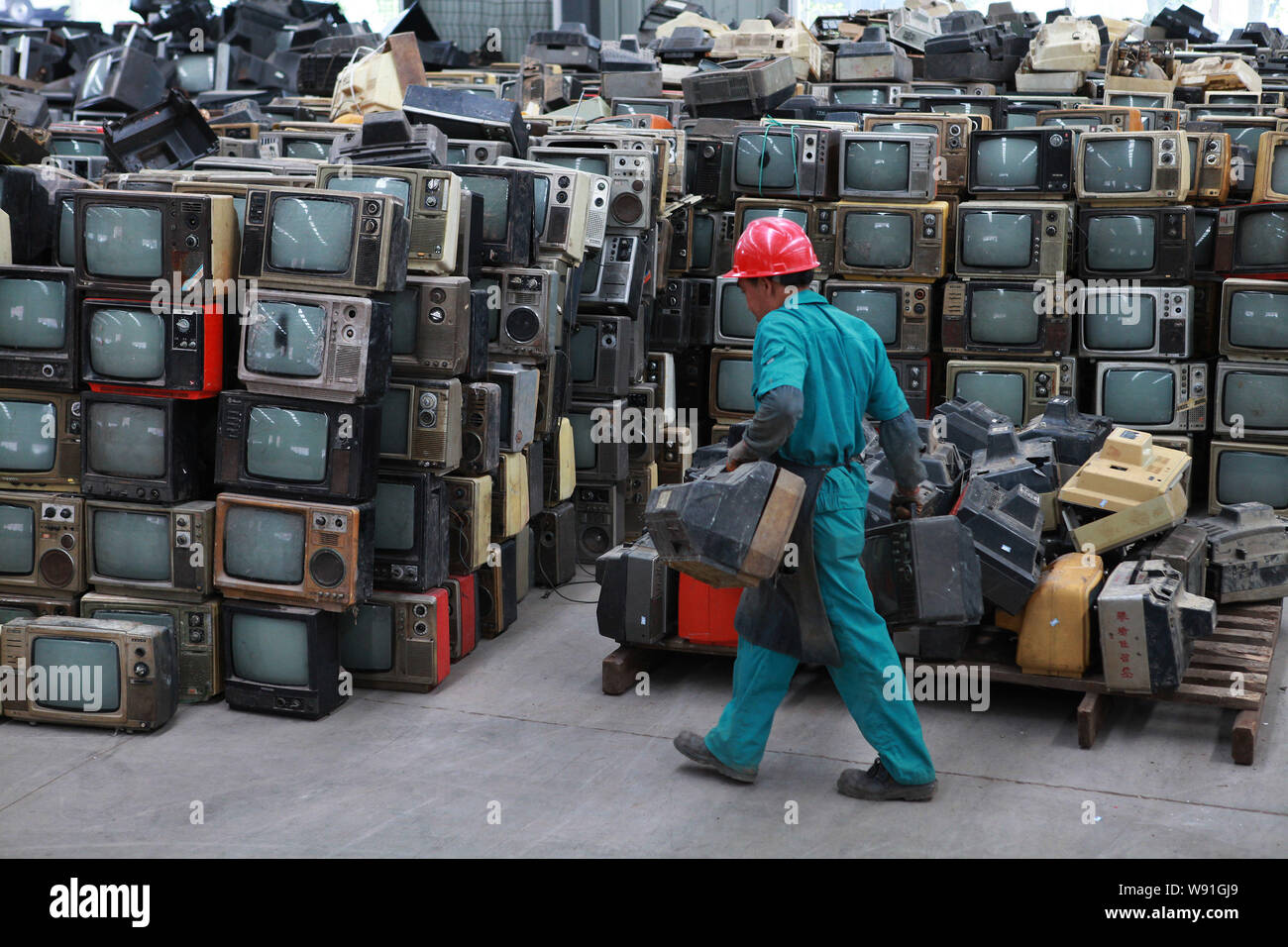 --FILE--Un travailleur chinois a dépassé jeté CRT (tube cathodique) téléviseurs à démonter qu'il passe devant des tas de d'autres à un recyclage Banque D'Images
