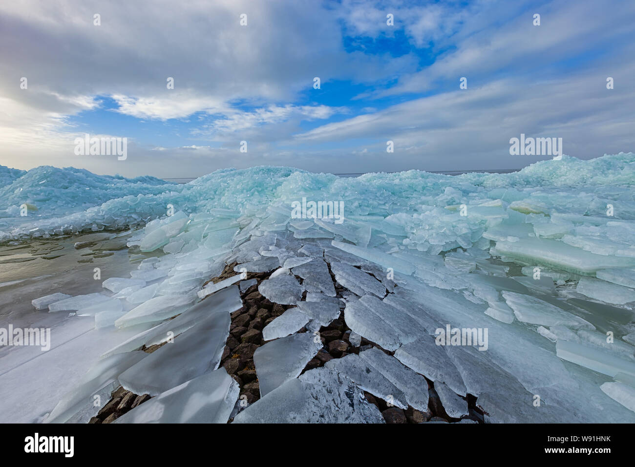La durée de la glace sur la rive d'un lac gelé avec un sly bleu et les nuages blancs dans l'arrière-plan - IJsselmeer, Pays-Bas Banque D'Images