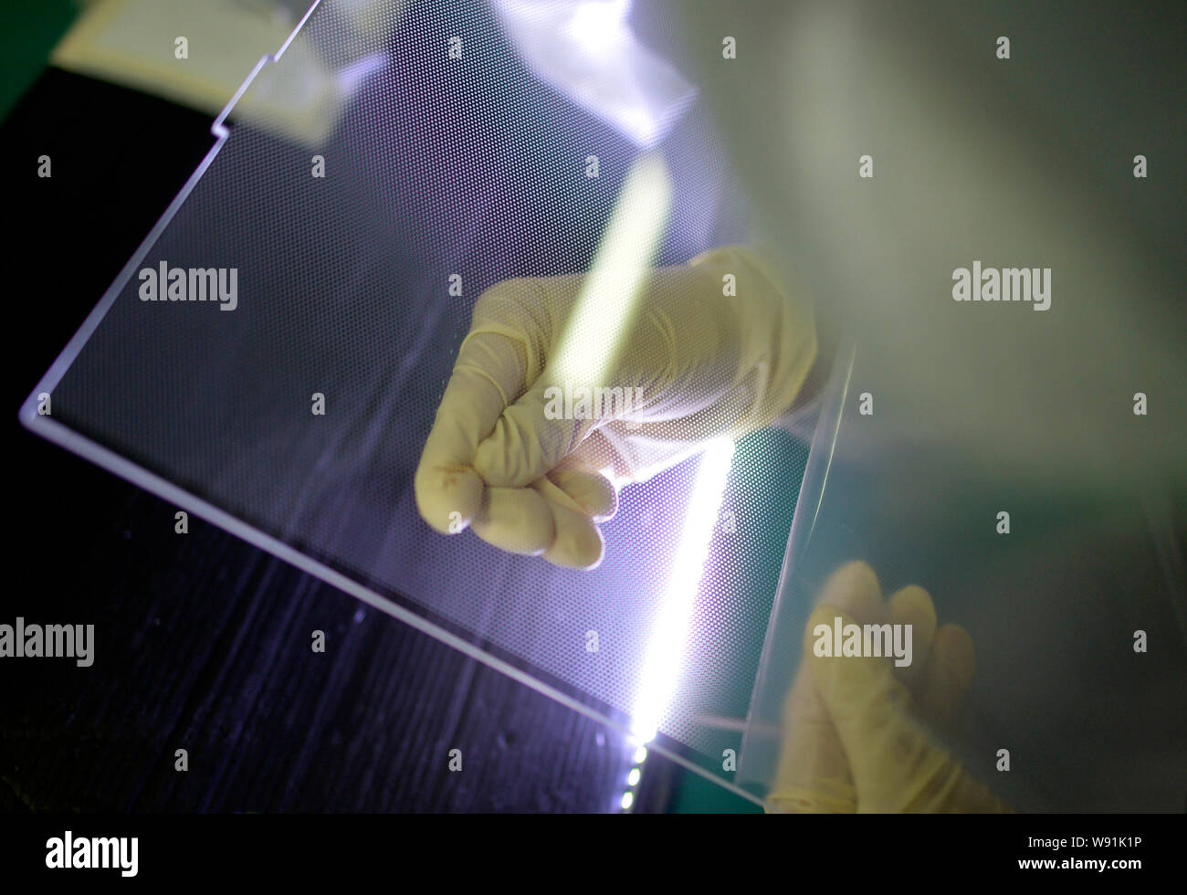 --FILE--Un travailleur chinois examine une composante d'une télévision à écran du panneau de commande à l'usine de Wuhan Hengsheng Optoelectronic Co., Ltd. à Wuhan City, Banque D'Images