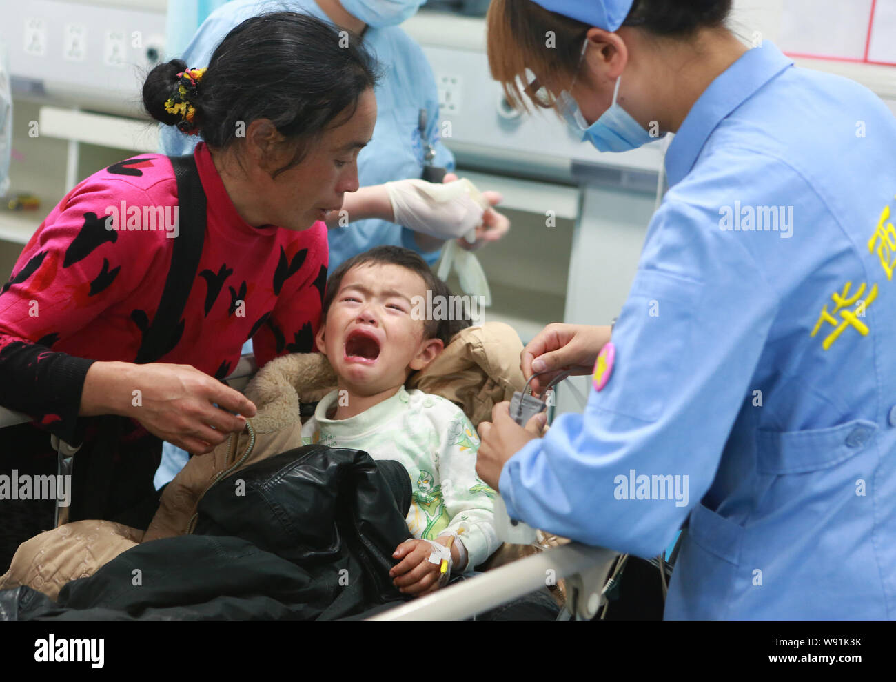 Un enfant (centre), qui est blessé dans le tremblement de terre qui s'est passé à la ville de Longmen, Lushan county, la ville de YaAn, cris tout en recevant un traitement médical Banque D'Images