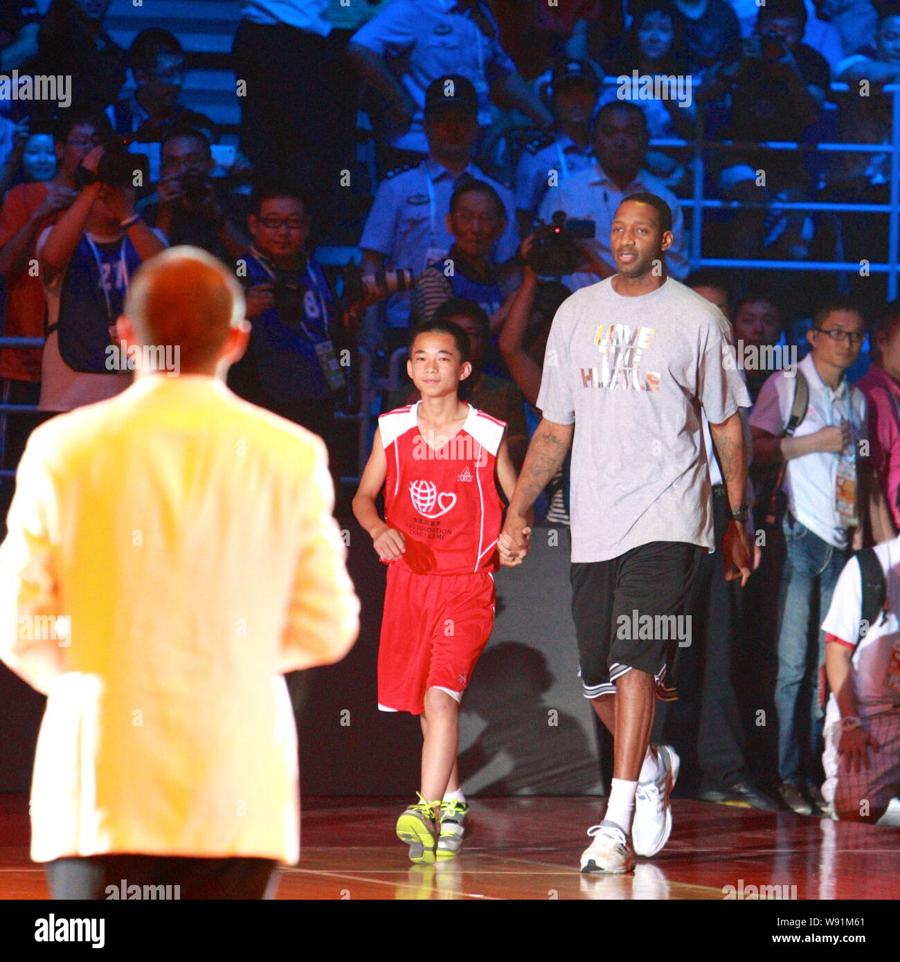 Ancienne star de la NBA Tracy McGrady, dos droit, marche avec un jeune joueur au cours de la Yao Foundation charity match à Beijing, Chine, 1 juillet 2013. Banque D'Images