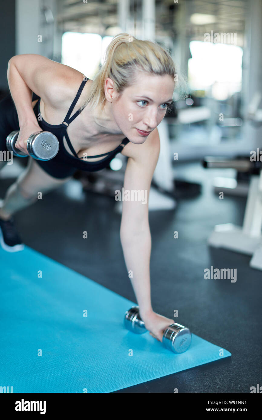 Jeune femme muscle triceps haltère trains durant l'exercice dans le centre de remise en forme Banque D'Images