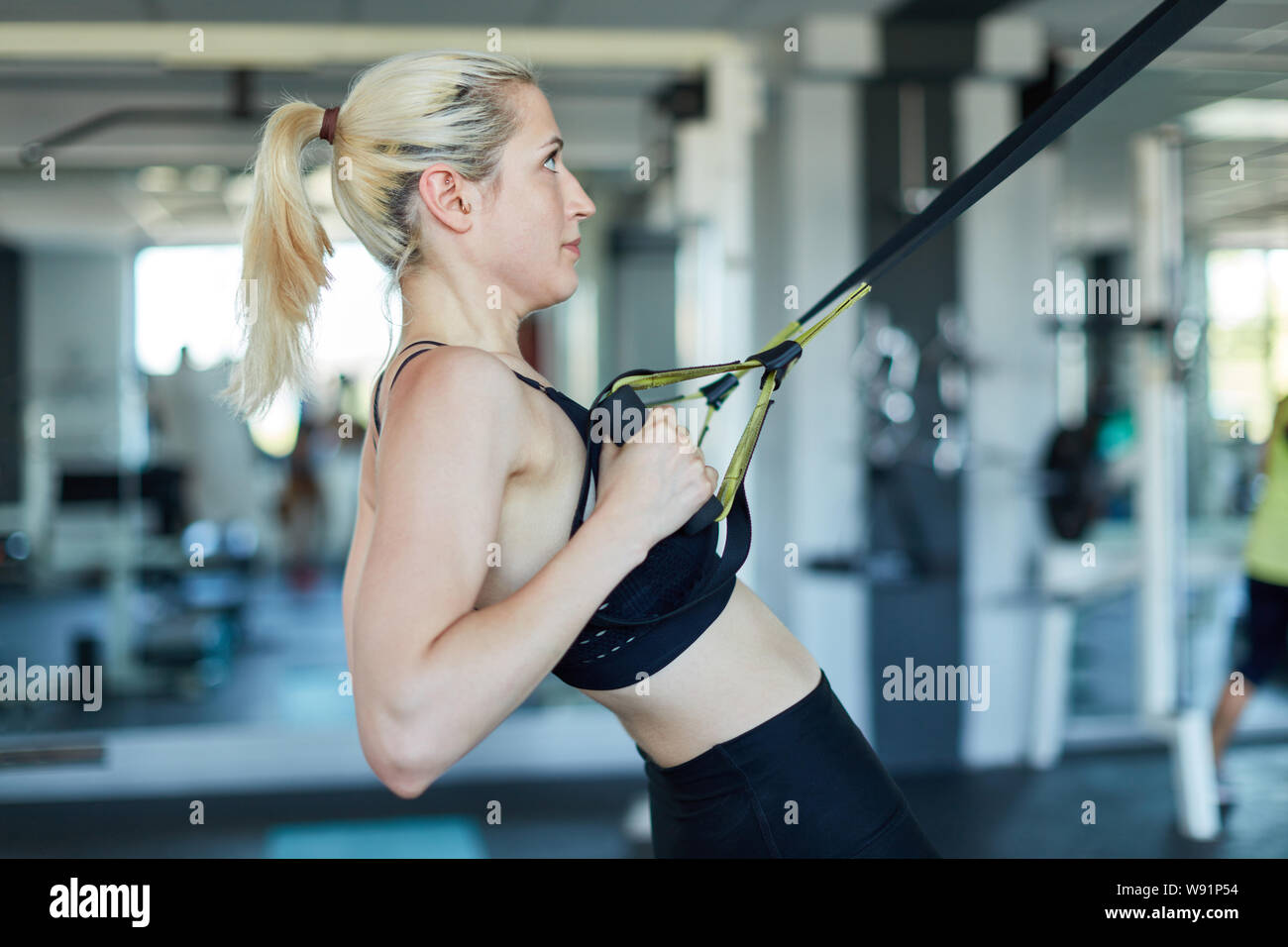Jeune femme dans la salle de remise en forme et de la force de l'endurance avec dos sling training Banque D'Images