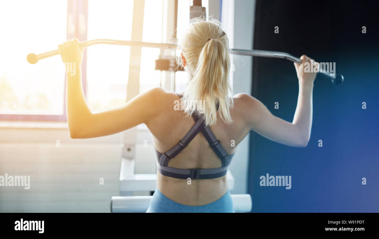 Retour d'une femme à l'arrière de la formation sur Latzug dans le centre de remise en forme Banque D'Images