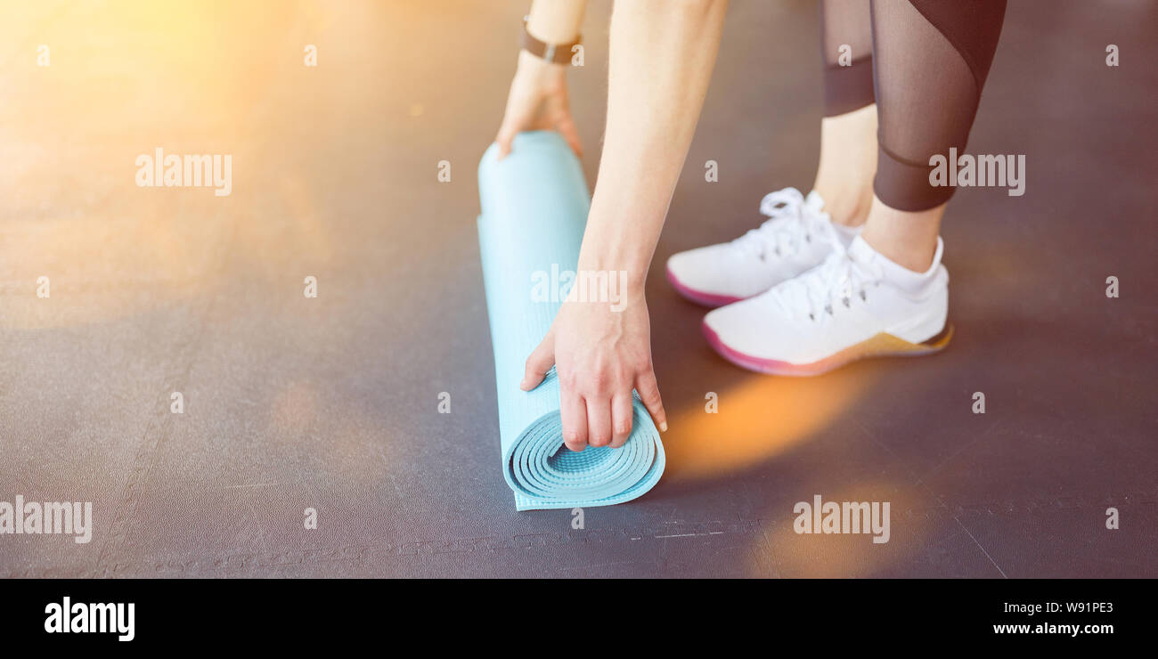 Jeune femme roule sur un tapis de yoga après l'exercice de bien-être Banque D'Images