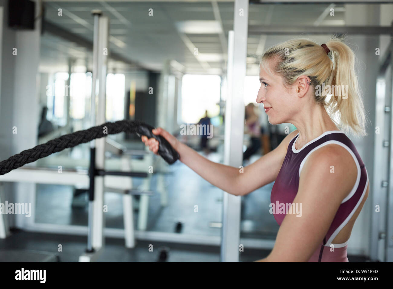 Jeune femme sportive dans la bataille d'entraînement Crossfit corde comme Formation Banque D'Images