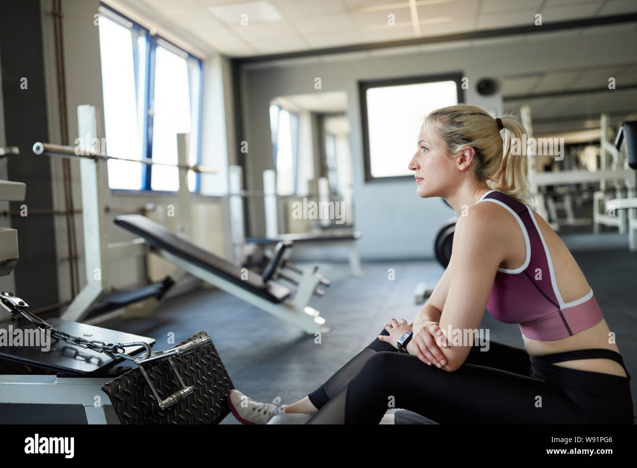 Jeune femme assise pensivement sur le câble dans la salle de sport dans une pause formation Banque D'Images