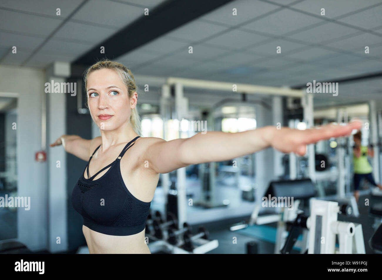 Femme étendant ses bras dans la salle de sport alors que l'étirement avant l'entraînement Banque D'Images