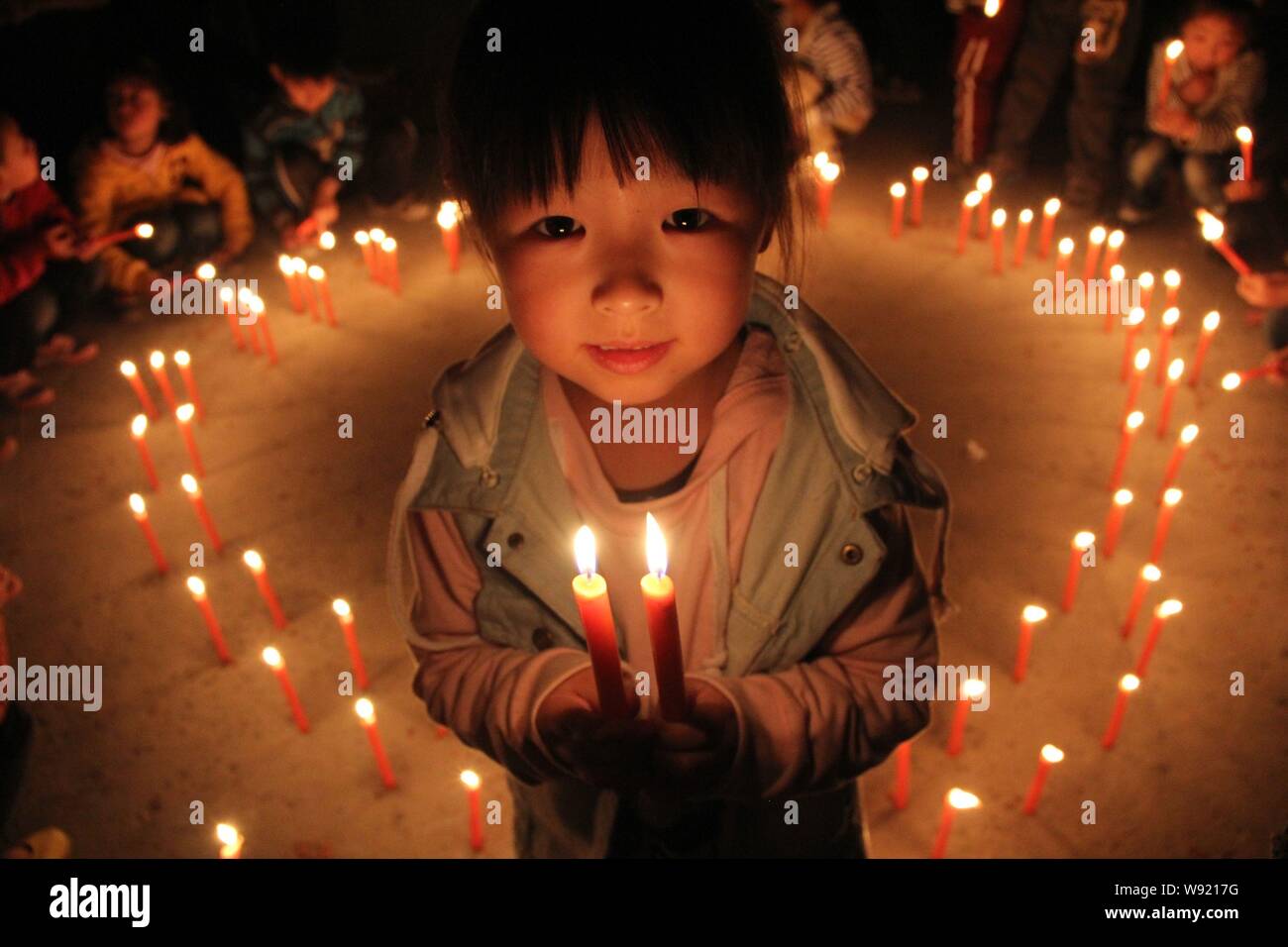 Une petite fille chinoise détient des bougies pour le deuil pour les  victimes du tremblement de terre de YaAn lors d'un mémorial à Anyang,  province du Henan, Chine centrale 25 Photo Stock -