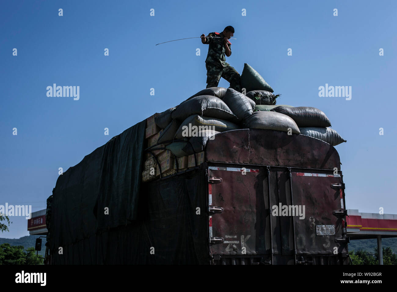 Un soldat de la défense de la frontière chinoise sent un bâton d'acier il percé dans les sacs sur un camion pour rechercher des médicaments à un point de contrôle près de la frontière de Menton Banque D'Images