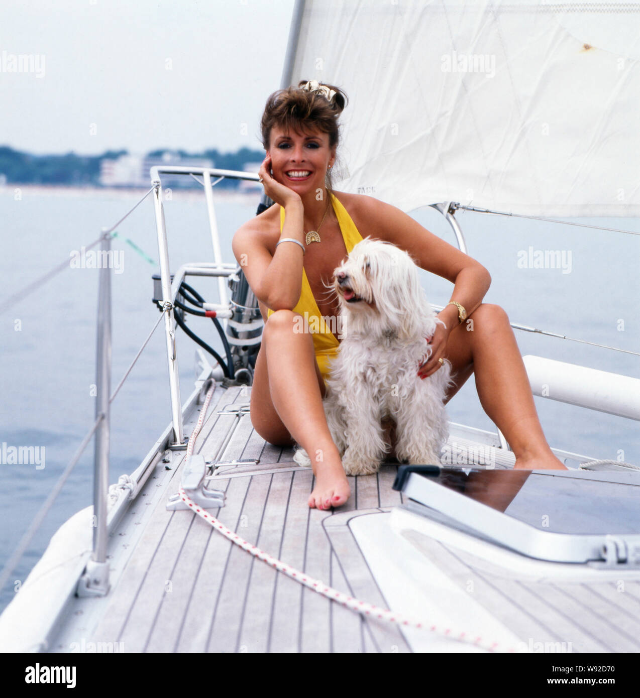 Die britische-Schlagersängerin deusch Sheer Ireen posiert langhaarigen Tibet-Terrier mit ihrem auf einem Segelboot im Badeanzug, Ende des années 1980 er Jahren. La chanteuse pop anglo-allemande pure Ireen pose fièrement avec son poil long terrier du Tibet sur un bateau à voile dans un maillot à la fin des années 80. Banque D'Images