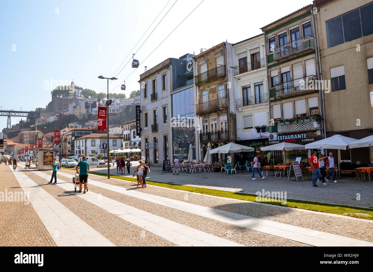 Porto, Portugal - 31 août 2018 : Les gens de marcher sur la promenade au bord du fleuve Douro lors d'une journée ensoleillée. Le remblai est plein de restaurants, bars et caves à vin utilisé pour l'échéance du célèbre vin de porto. Banque D'Images