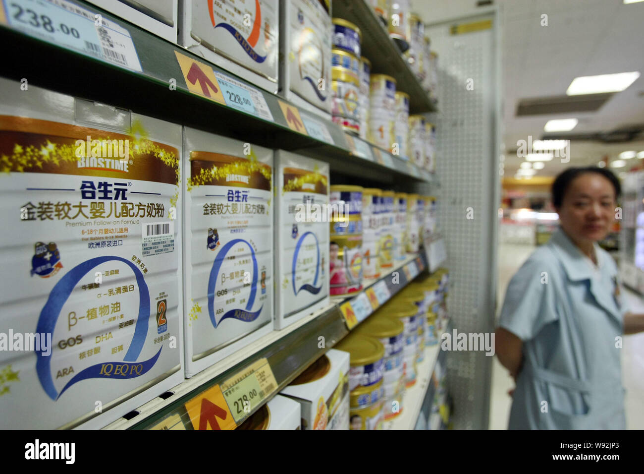 --FILE--un employé chinois se place en avant des boîtes métalliques de la société chinoise Biostime premium suite à la vente dans un supermarché à Shanghai, Chine, le 2 juillet 2013. Banque D'Images