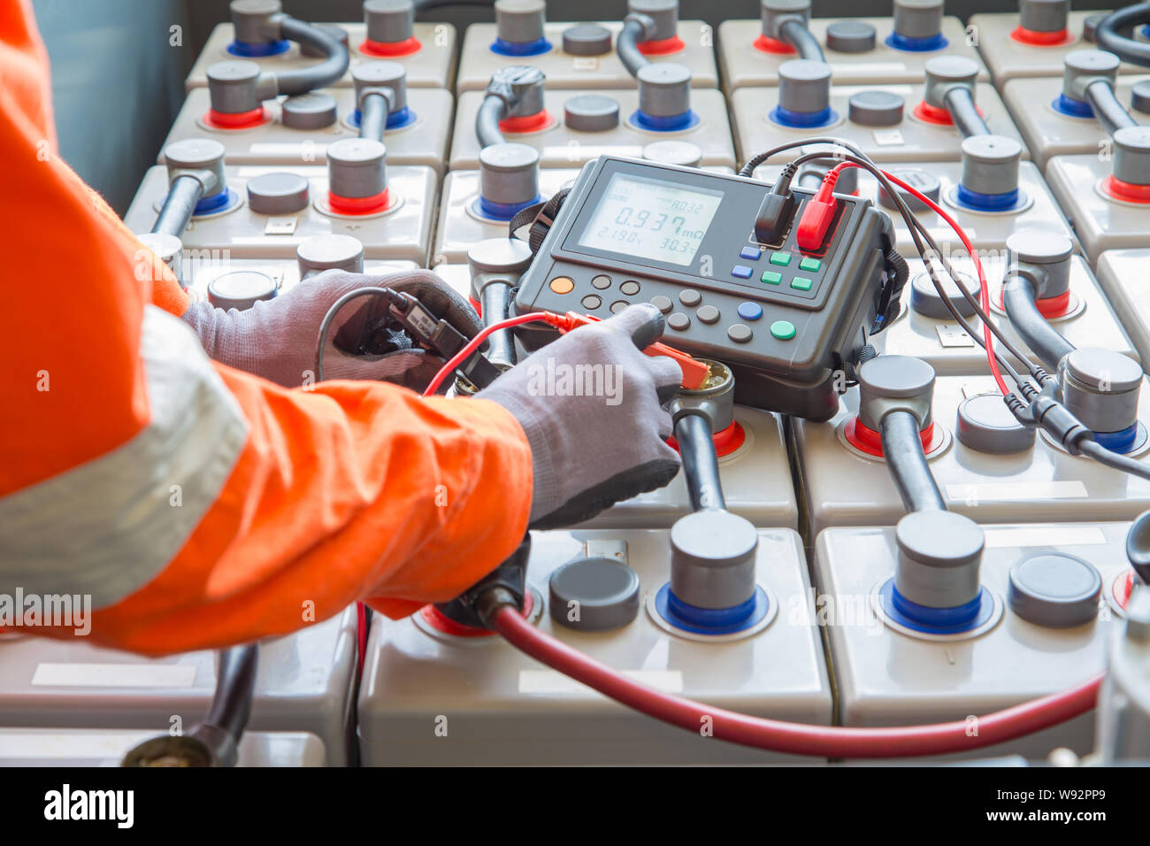 Spécialiste électricien inspecter, vérifier la tension et la résistance interne de la batterie Les batteries à l'aide à la maintenance préventive, l'extraction de pétrole et de gaz oc Banque D'Images