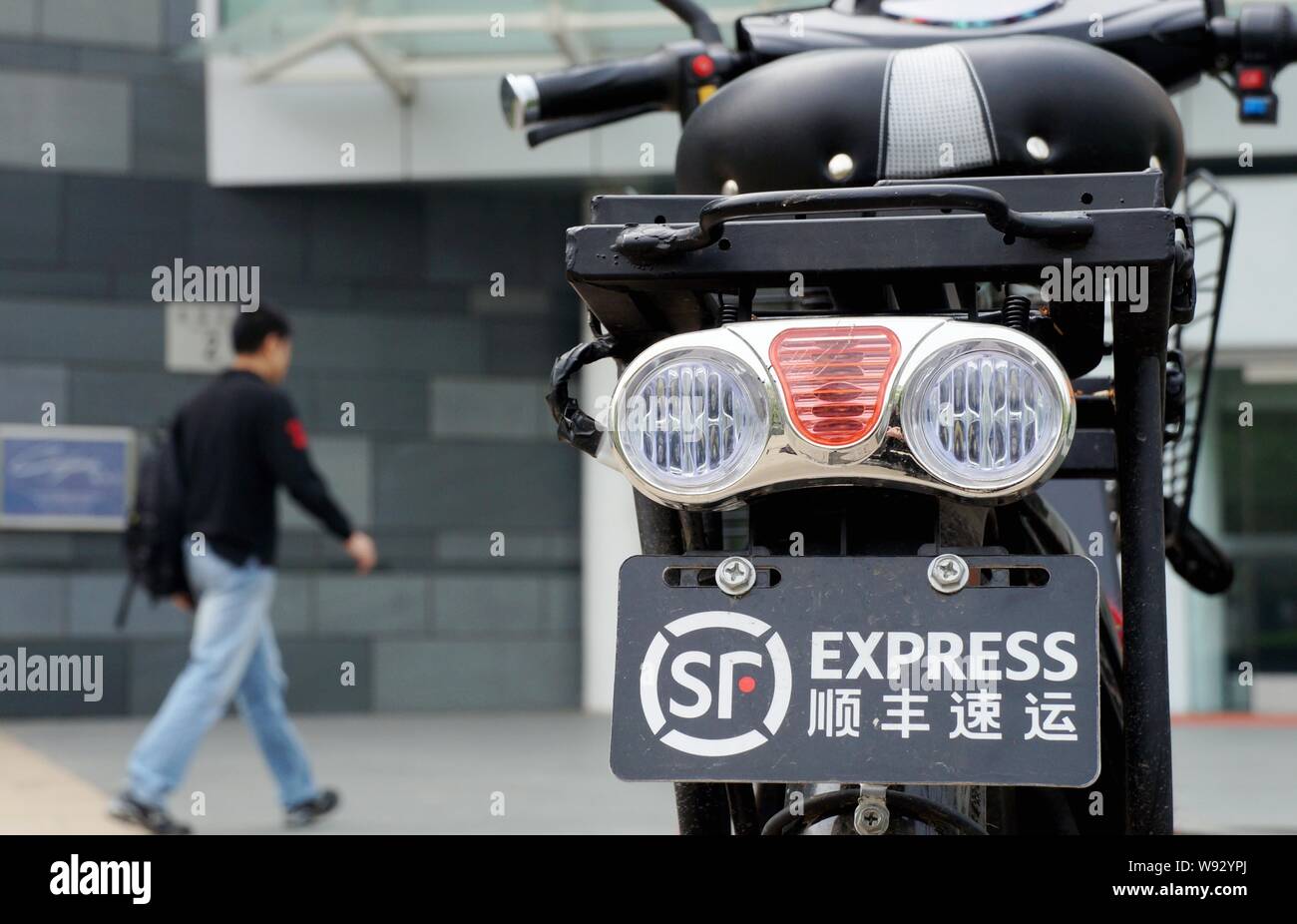 --FILE--un piéton passe devant le vélo électrique d'un courrier de SF Express à Pékin, Chine, 22 avril 2012. Société de capital chinois Citic Cap Banque D'Images