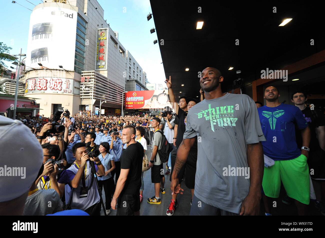 Star de la NBA Kobe Bryant, sourires, avant de jeter un terrain de basket-ball à une foule de fans lors d'un événement promotionnel dans un magasin de vêtements de sport Nike dans un shopp Banque D'Images