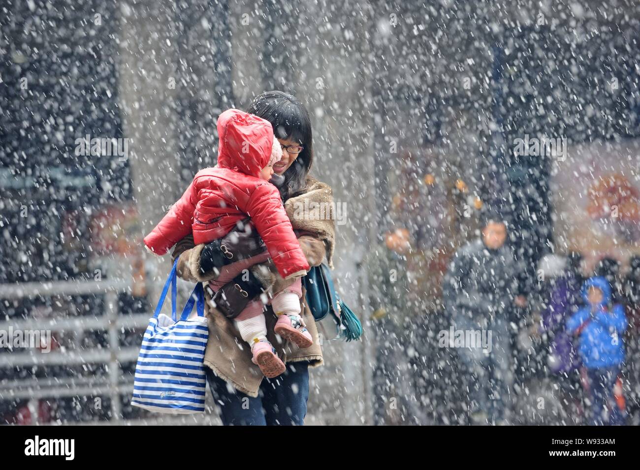 --FILE--une mère chinoise porte son enfant dans la neige lourde à la gare de Wuchang à Wuhan, province de Hubei, Chine centrale 8 février 2013. Banque D'Images