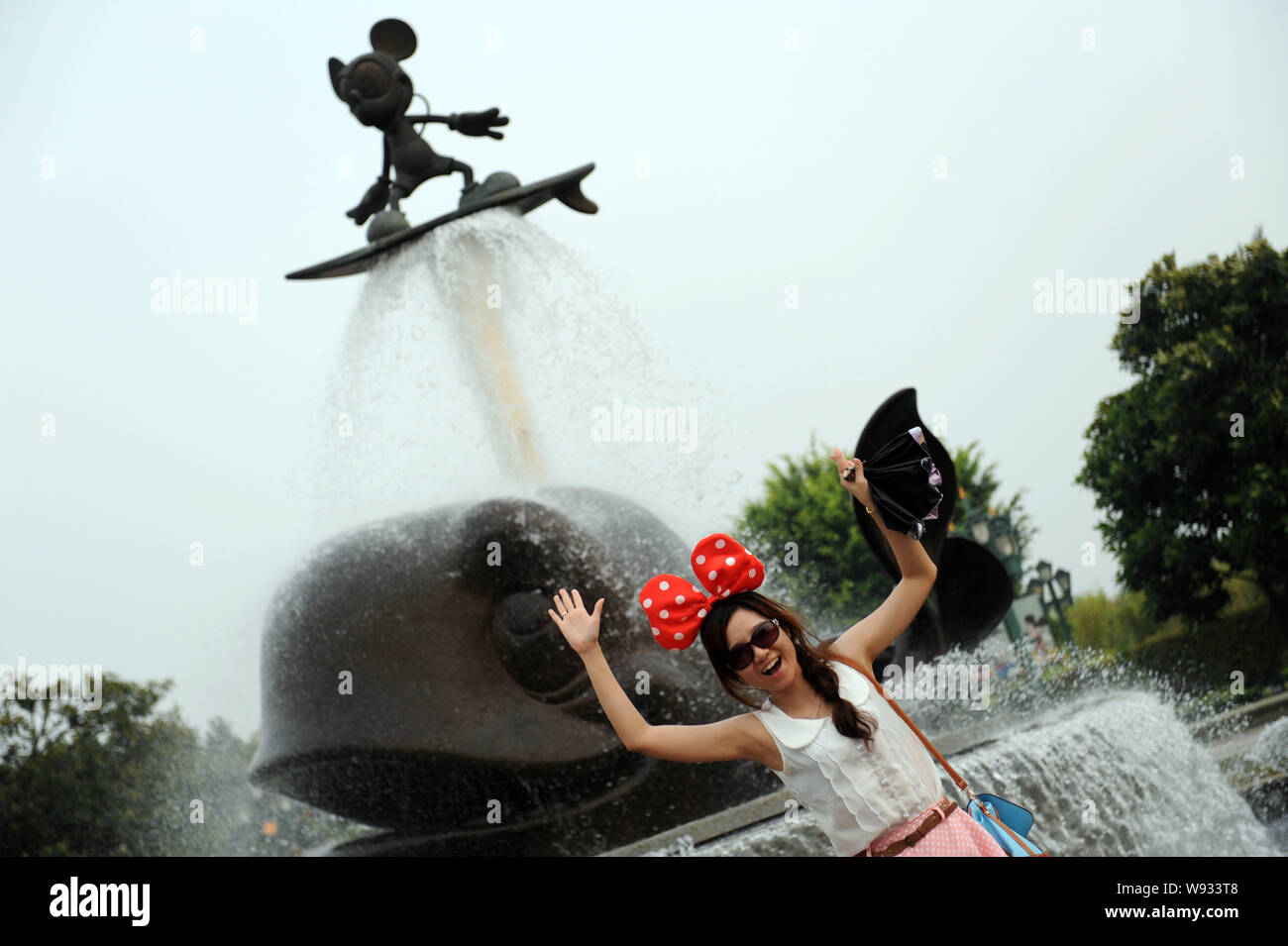 --FILE--un touriste pose avec une fontaine avec Micky Mouse au Hong Kong Disneyland Resort à Hong Kong, Chine, 22 juillet 2012. Les dernières escal Banque D'Images