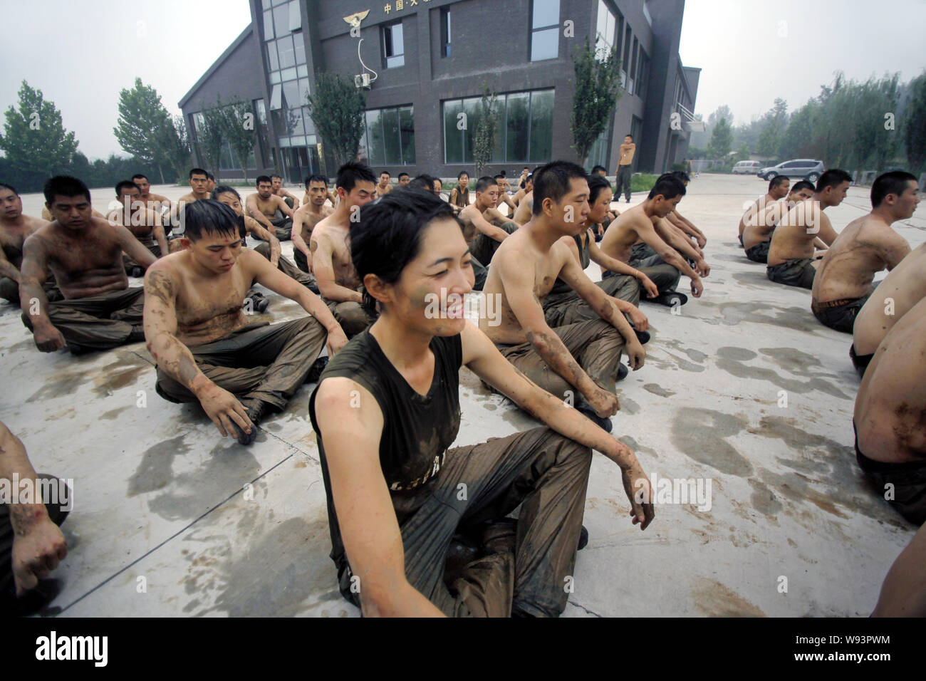 --FILE--stagiaires féminins et masculins s'asseoir sur le sol et se reposer après avoir rampé dans la boue lors d'un programme de formation de garde du corps au camp d'initialisation de Gengis secu Banque D'Images