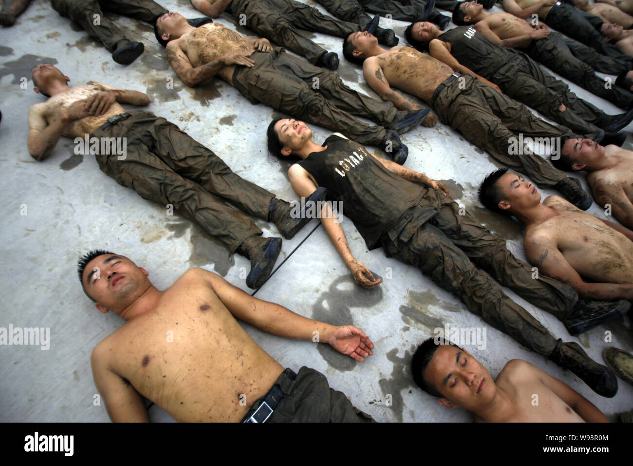 --FILE--stagiaires féminins et masculins se coucher sur le sol et reste après avoir rampé dans la boue lors d'un programme de formation de garde du corps au camp d'initialisation de Gengis secu Banque D'Images