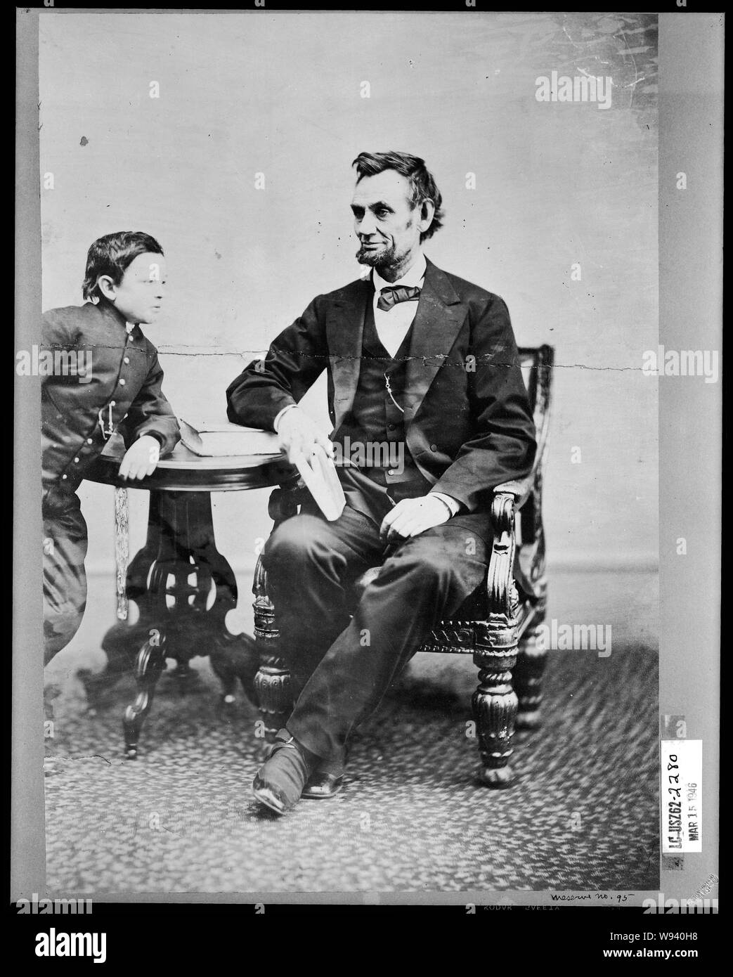Abraham Lincoln, assis et tenant un livre, avec son fils Thomas (TAD) s'appuyant sur une table Banque D'Images