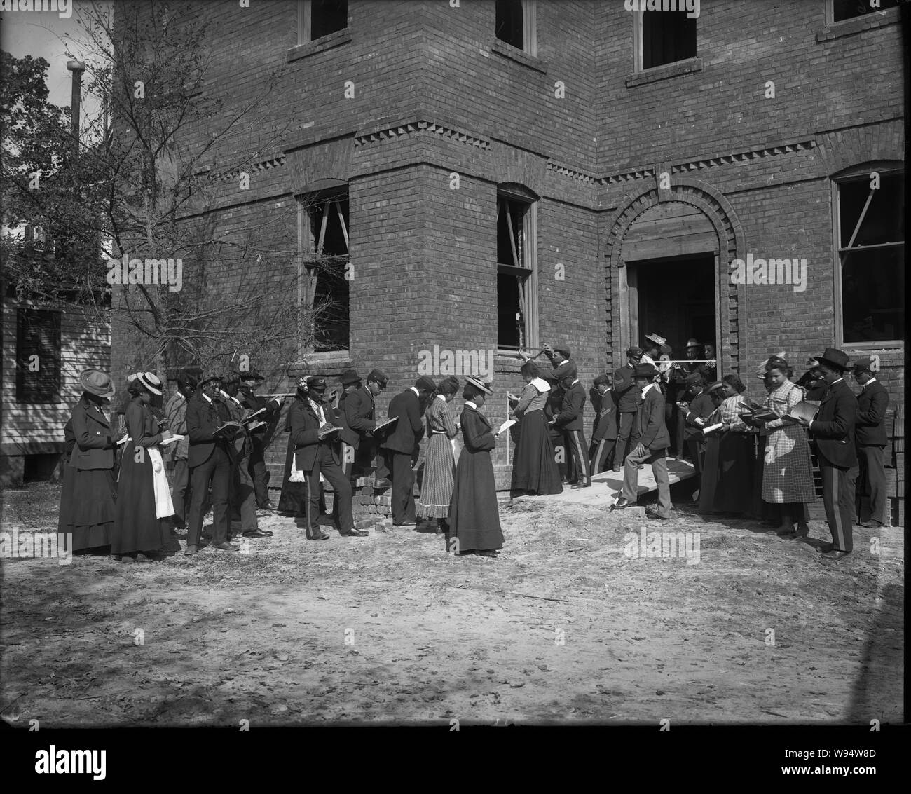 Les hommes africains-américains et les femmes les élèves à l'extérieur un bâtiment en brique avec des ordinateurs portables à la normale et de l'Institut Tuskegee, Alabama Industrielle Banque D'Images