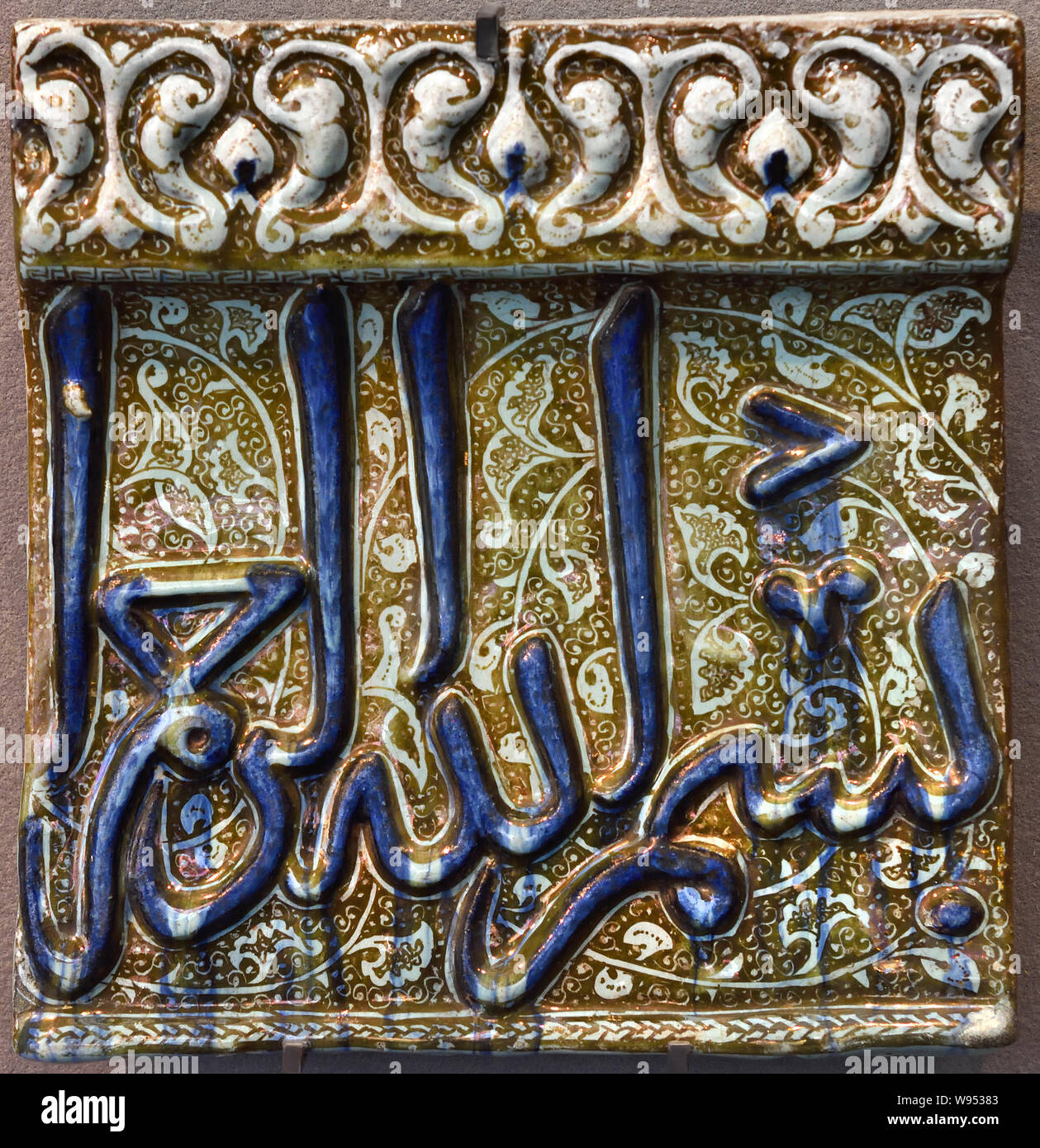 Tuile avec Bismillah, fin 13e - début 14e siècle, l'Iran, en Céramique moulée décor glaçage glacé. L'écriture arabe est utilisé pour noter plusieurs langues, principalement l'arabe, persan, turc et urdu. . Parfois, des lettres traitées comme des motifs décoratifs sont méconnaissables. Plusieurs objets montrent les mêmes mots (bismillah : 'au nom de Dieu, le Clément, le Miséricordieux") écrit dans des styles différents. Cette formule ouvre 113 des 114 sourates du Coran. Banque D'Images