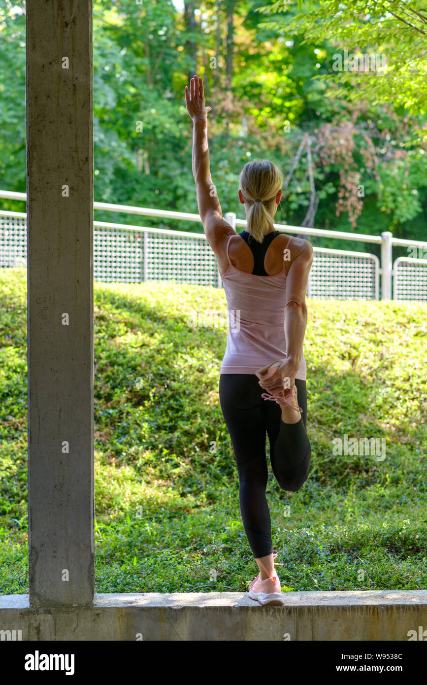 Athletic woman stretching exercices d'échauffement des muscles la jambe avant un entraînement et un bras vers le haut Banque D'Images