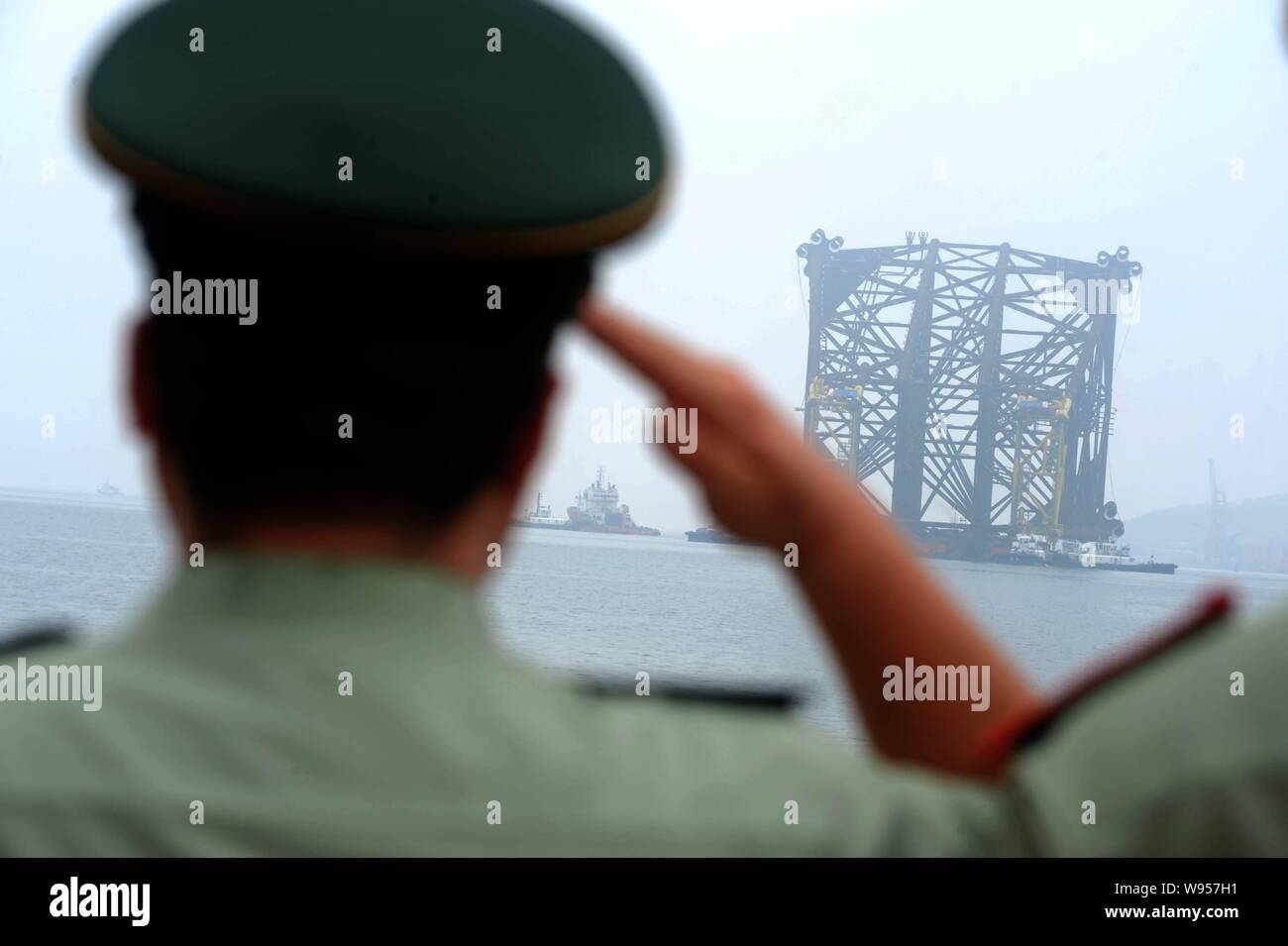 Les fonctionnaires de police armés peuples chinois salut à la Liwan 3-1 jacket construit par CNOOC avant son départ pour la mer de Chine du Sud à un Banque D'Images