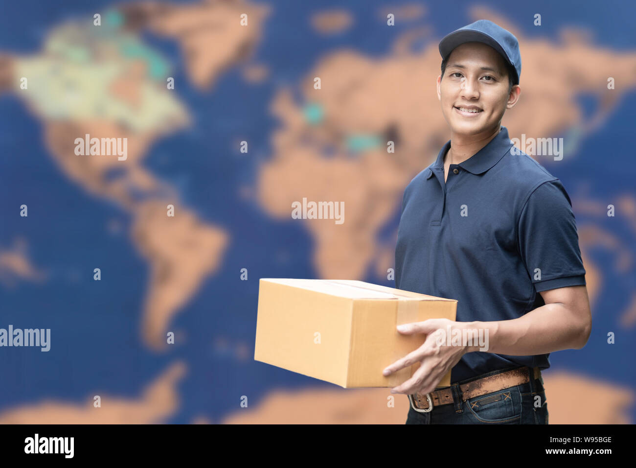 Livraison asiatique homme tenant une boîte en carton avec carte du monde en arrière-plan pour l'e-commerce et logistique concept. Banque D'Images