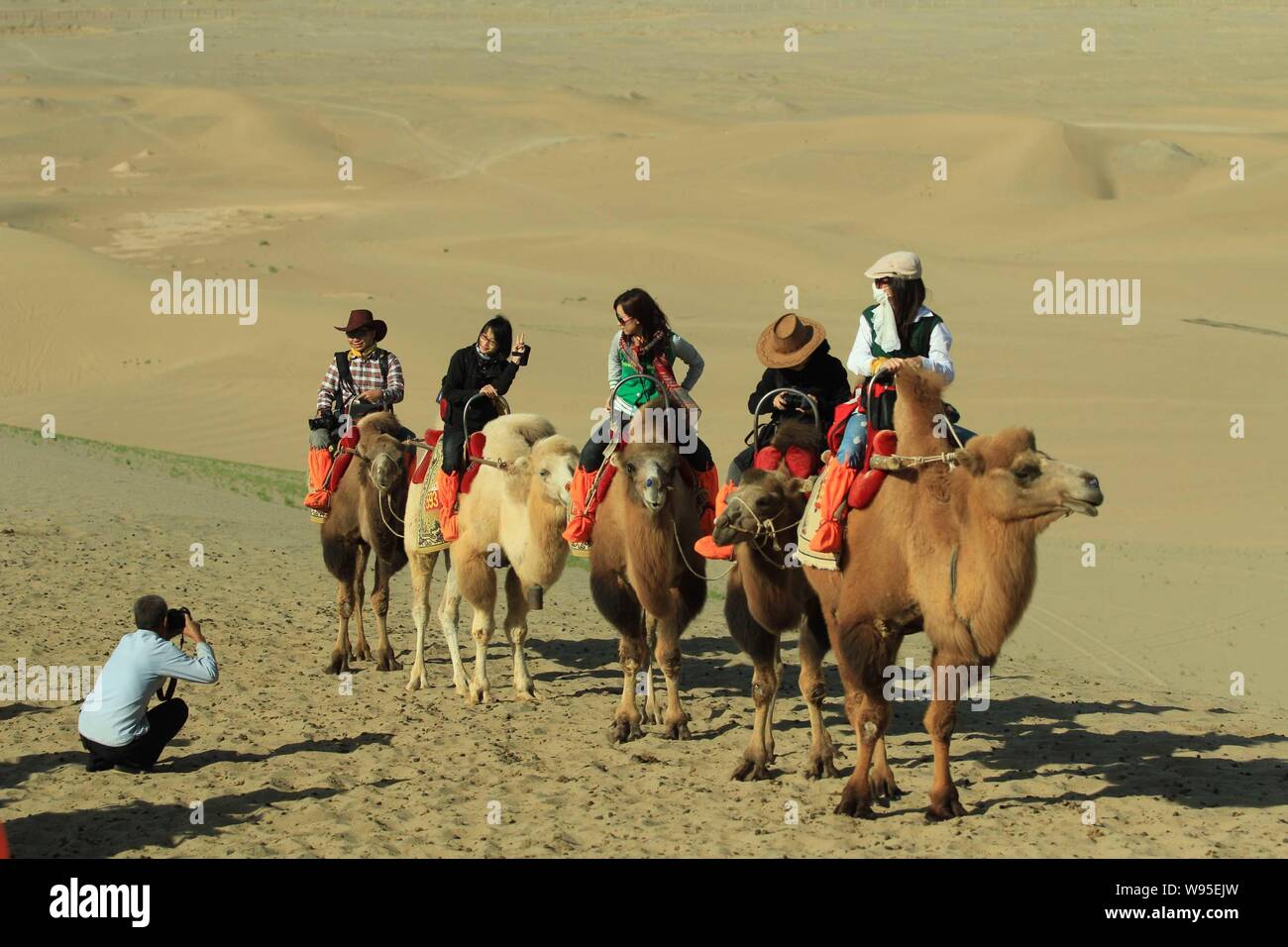 Les touristes monter des chameaux dans le désert dans le Croissant de lune (Yueyaquan) et le chant des montagnes de sable dans endroit pittoresque, au nord-ouest de la ville de Dunhuang Chines Banque D'Images