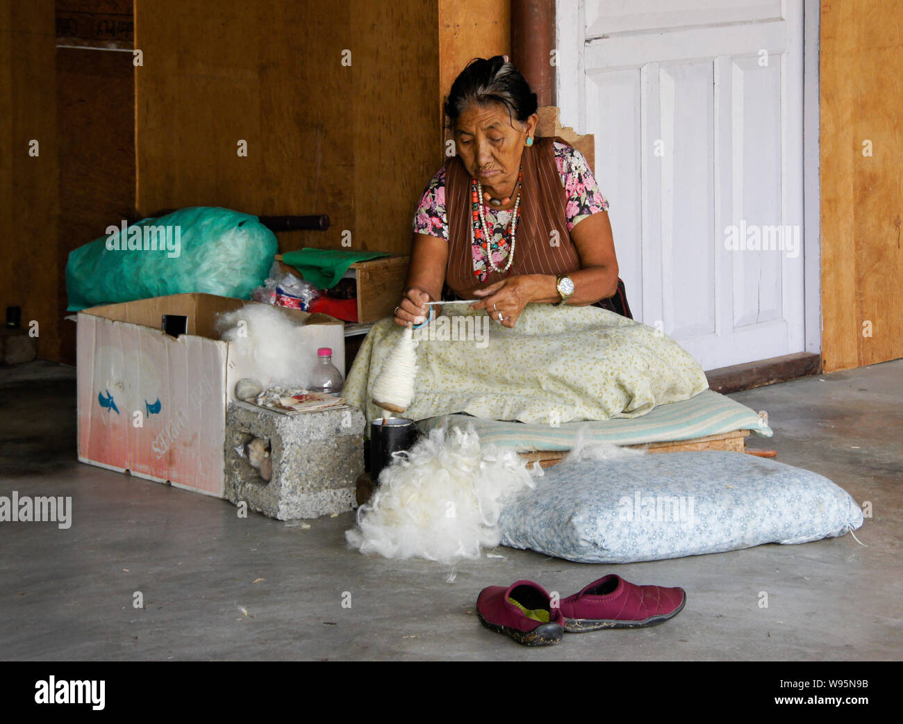 Femme Tibétaine âgée filage de la laine à un atelier de tapis dans Tashi-Ling communauté tibétaine près de Pokhara, Népal Banque D'Images