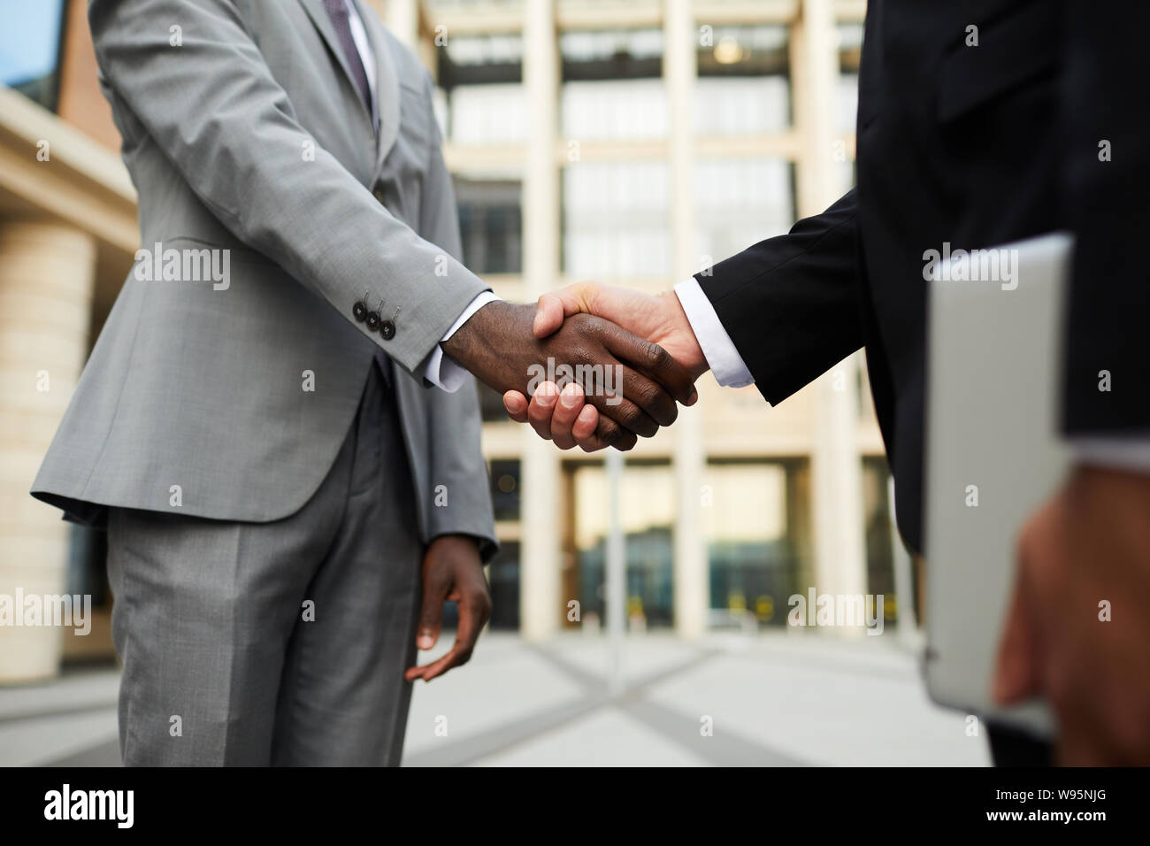 Close-up de gens d'affaires multiethniques en costumes standing and shaking hands ils chaque message d'autres avant de rencontrer à l'extérieur Banque D'Images