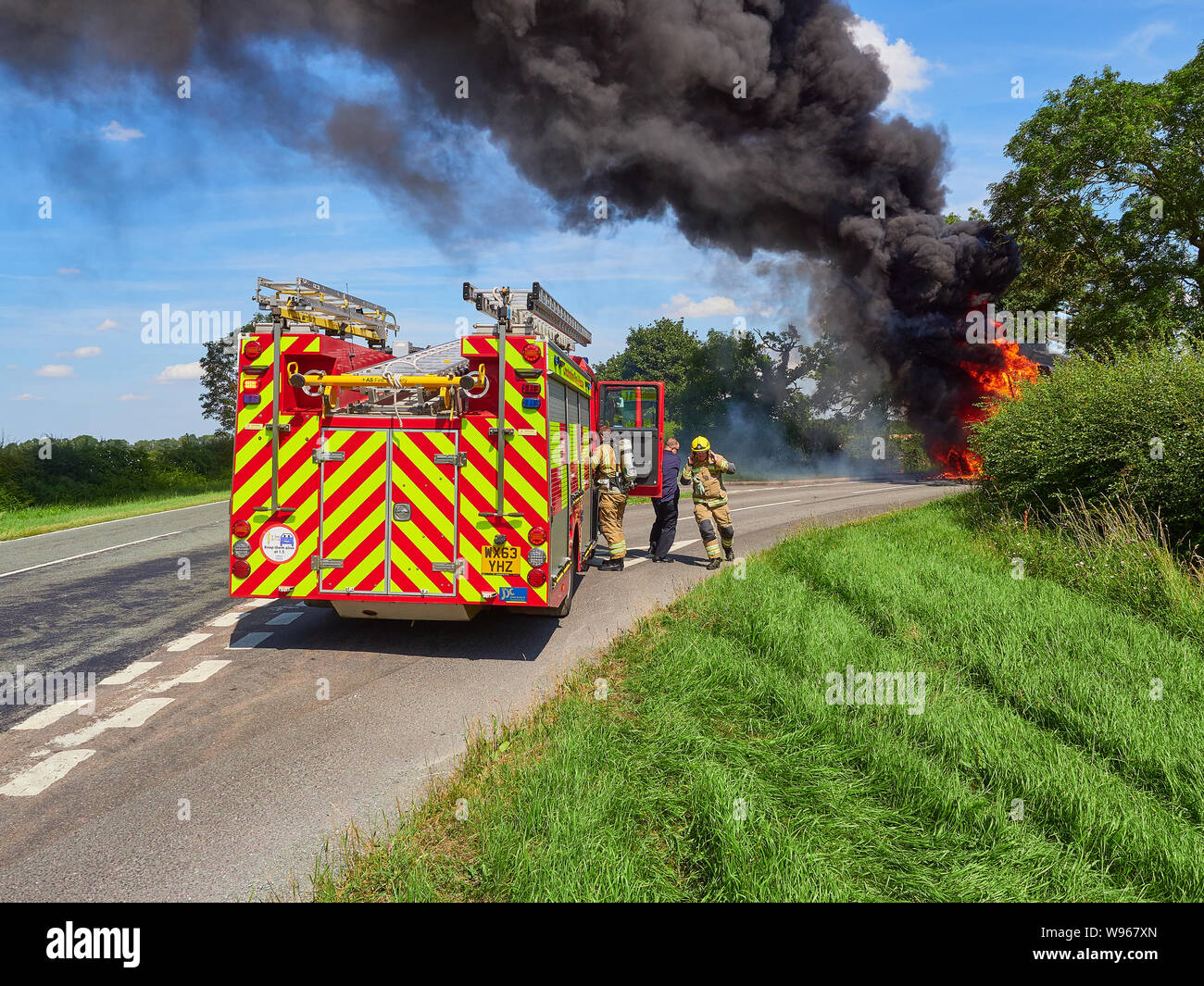 De la fumée noire s'affiche sur une route principale Lincolnshire Fire and Rescue arrive pour s'attaquer à un véhicule agricole incendie Banque D'Images