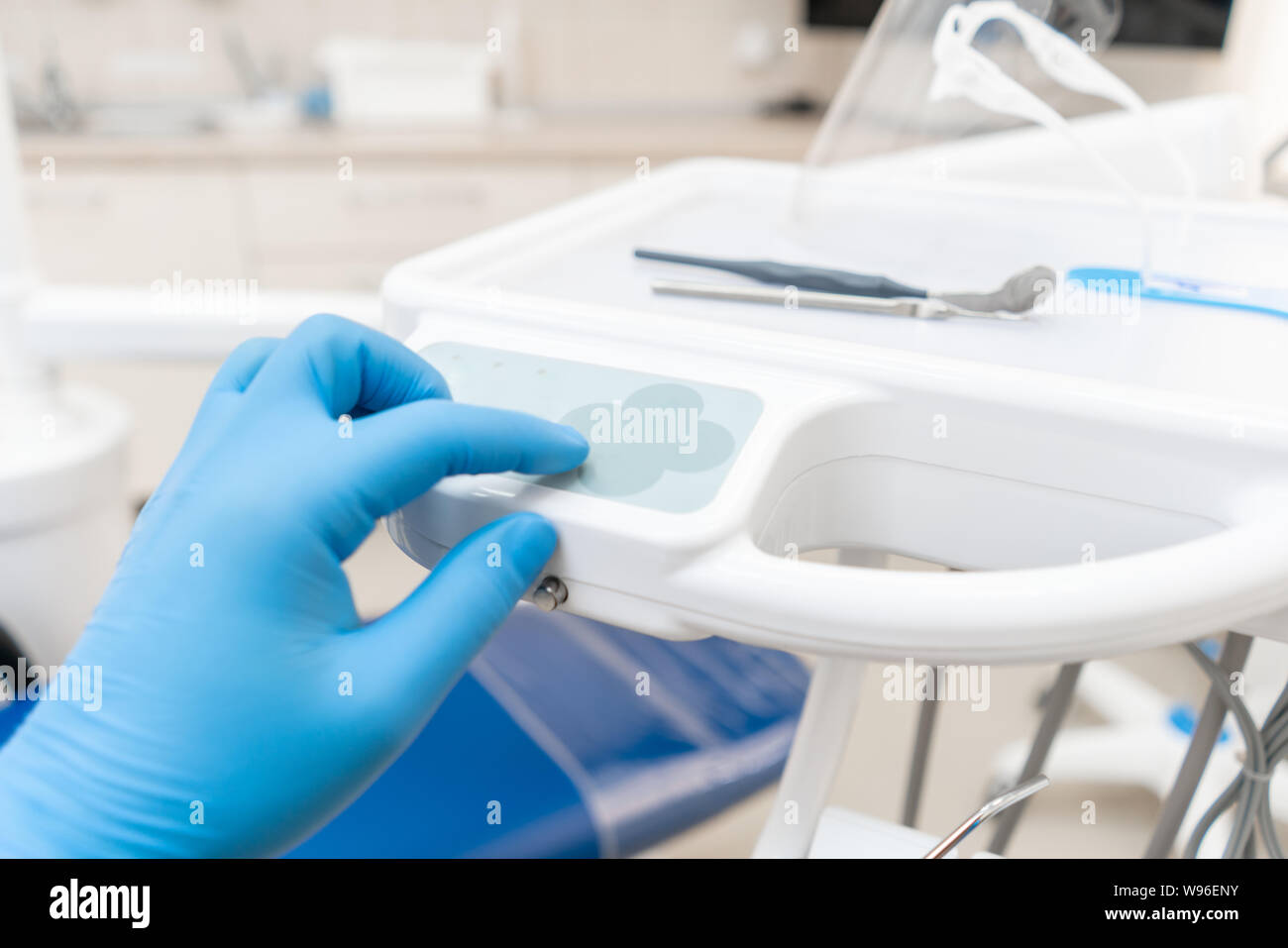 La main du dentiste dans la boîte à gants appuie sur les boutons de contrôle du président.. Travaux dentaires en clinique. Opération, remplacement des dents. Médecine, santé Banque D'Images