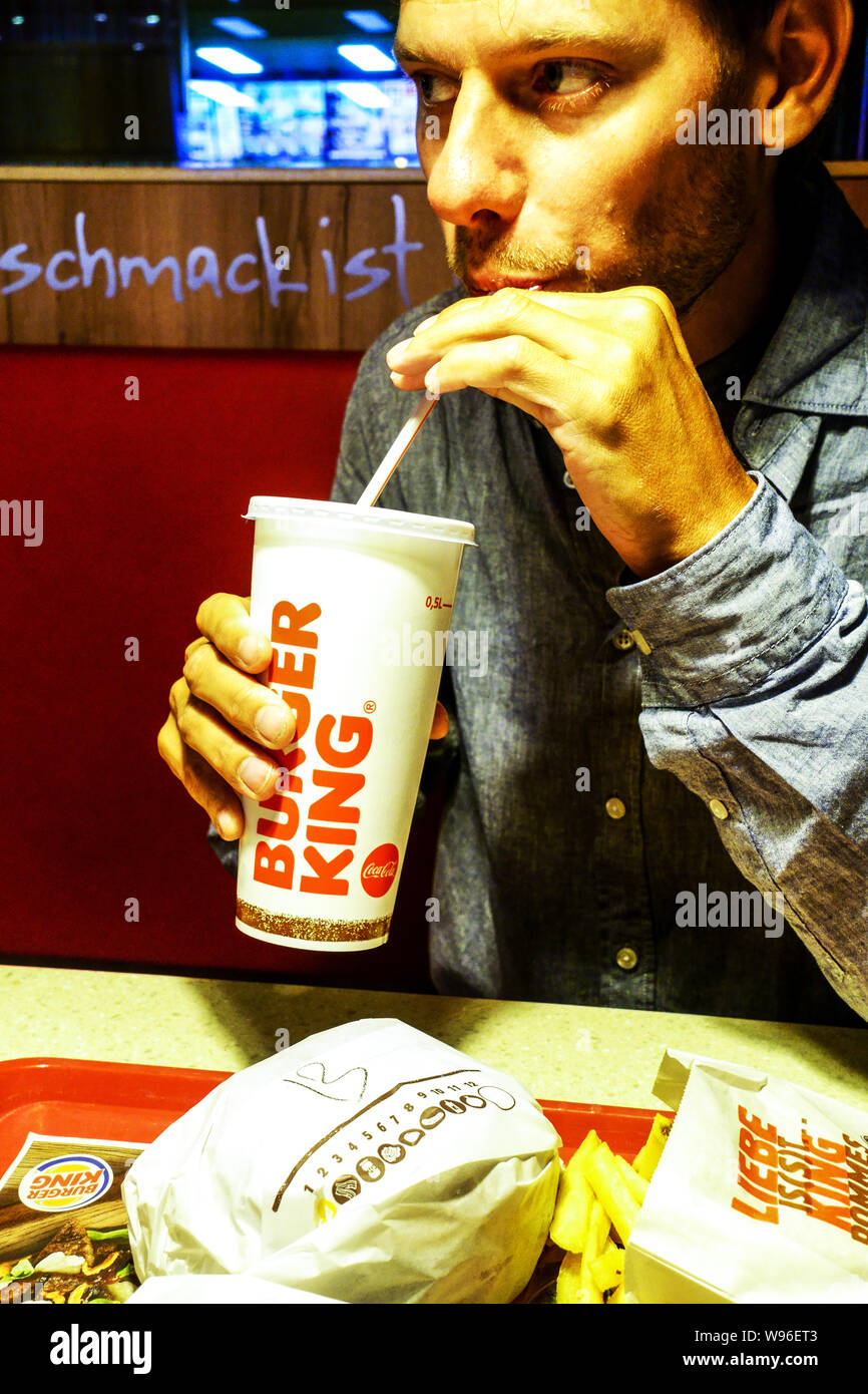 L'homme de boire avec une paille de la Burger King cup Banque D'Images