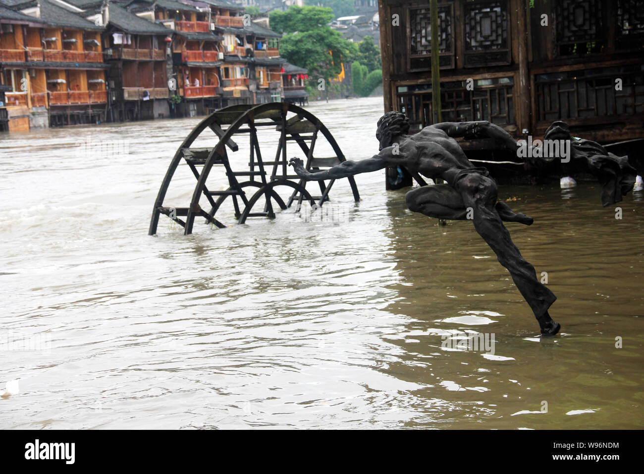 Une statue et maisons anciennes sont partiellement submergées par l'eau de la rivière Tuojiang inondées Rivière (Tuo) causés par les pluies torrentielles à Fenghuang (Phoenix) Banque D'Images