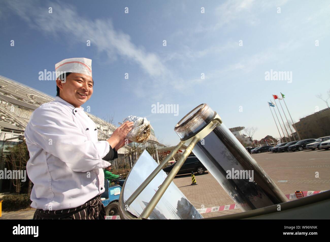 Un chef utilise un four solaire pour cuire les aliments à Shanghai, Chine de l'est la province de Shandong, 18 mars 2012. Les cuisinières solaires utilisent l'énergie de la lumière à la chaleur de la nourriture Banque D'Images