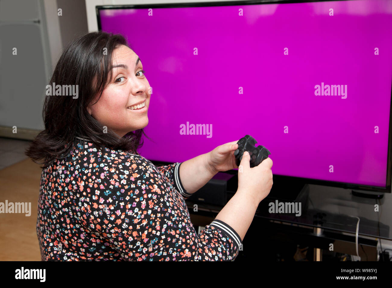 En face d'un écran blanc avec copie espace, une personne est à la recherche à l'épaule en souriant tout en ayant un bon temps à jouer aux jeux vidéo Banque D'Images