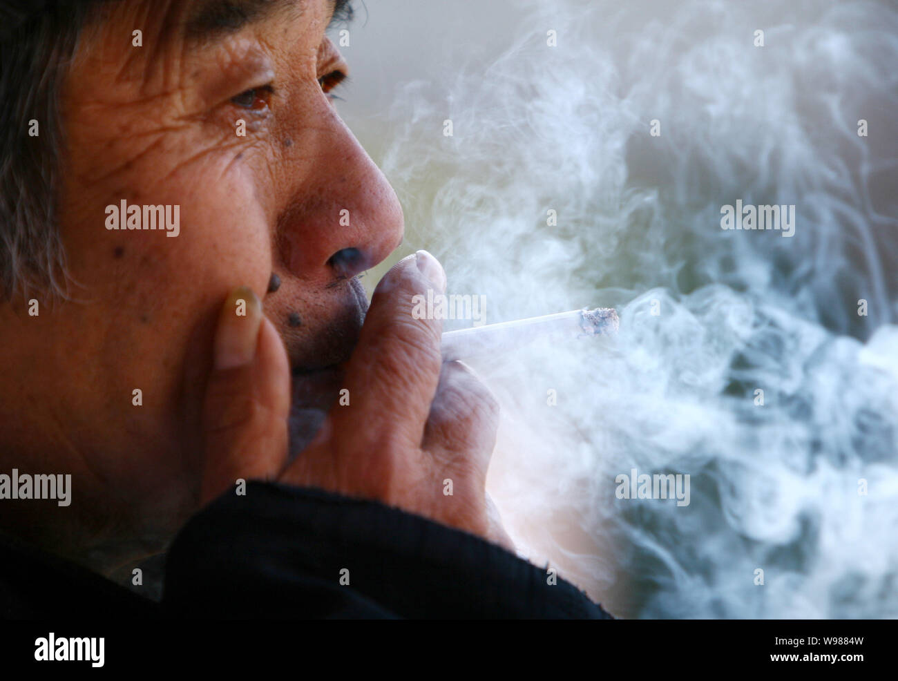Un Chinois fume dans la rue dans la ville de Fuyang, province de Anhui Chine de l'Est, 9 janvier 2011. En tant que signataire de l'Organisation mondiale de la Santé (OMS) Banque D'Images
