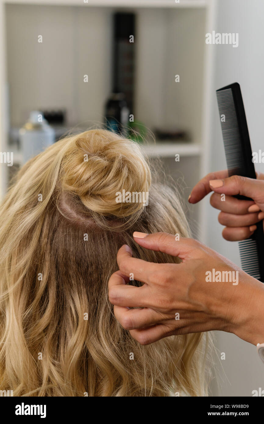 Hairtician s'appuie la bun. Hairstyle sur bob. Services de coiffure. La création de coiffures de soirée élégante à la mode coiffures des femmes. Processus d'h Banque D'Images