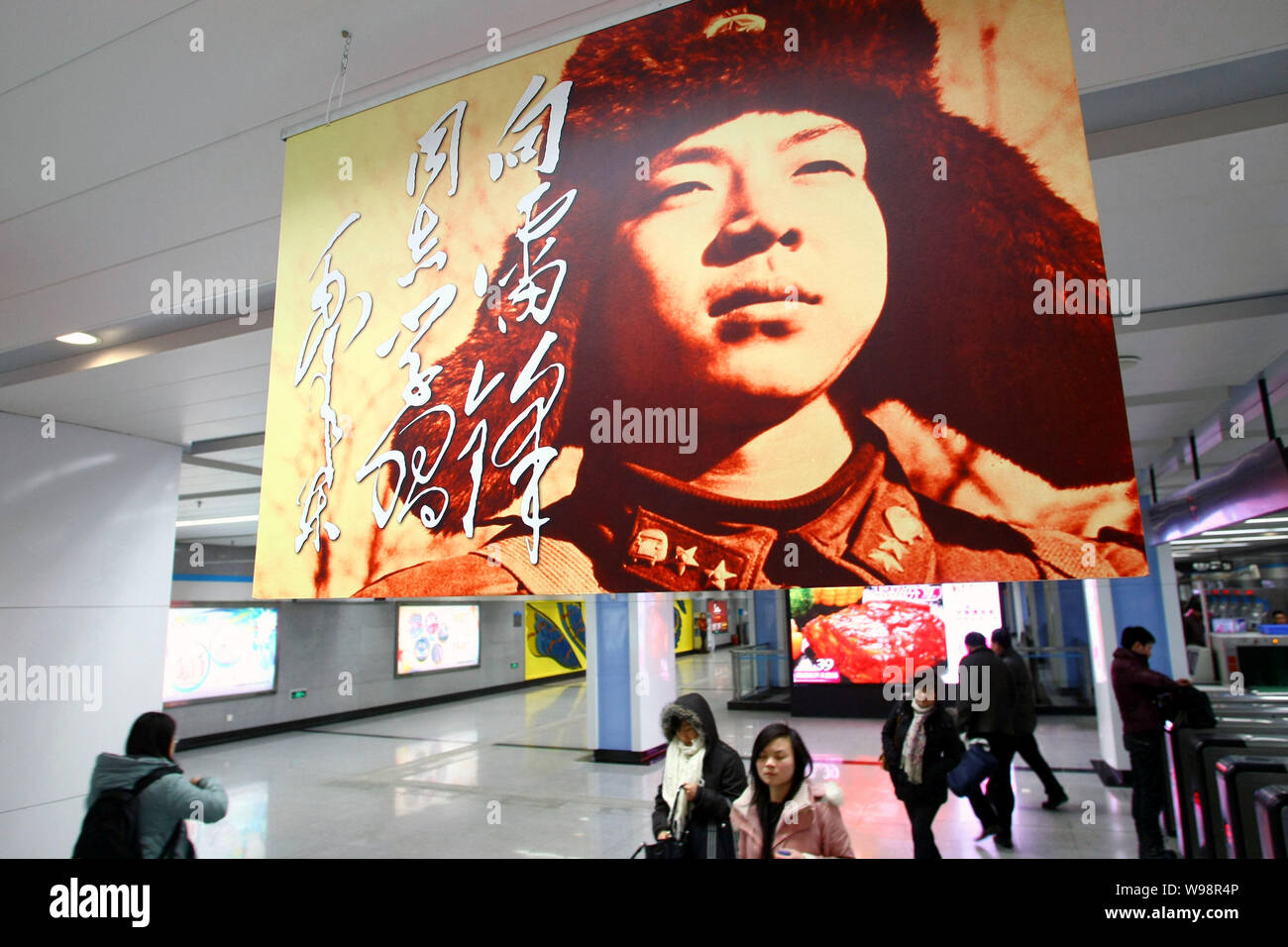 Voyageurs chinois à pied sous un poster de Lei Feng à la Station Dashijie à Shanghai, Chine, le 1 mars 2011. Lei Feng était un jeune soldat chinois du Banque D'Images